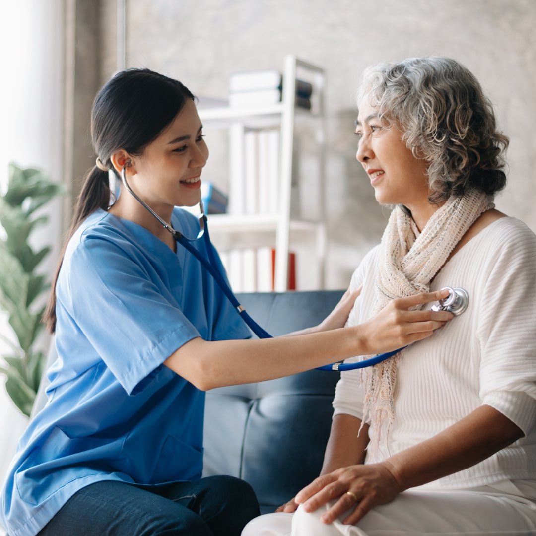 A nurse supporting a senior member during a check-up