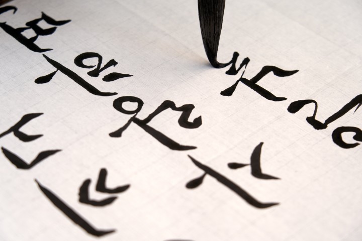 The hand of a person who writes brush strokes on paper