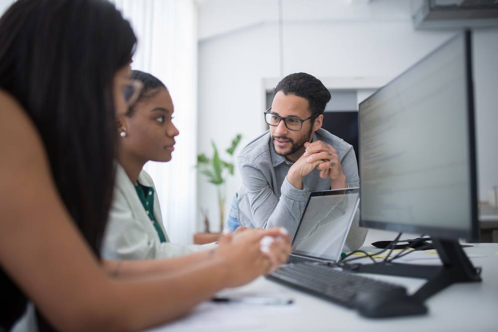 Coworkers talking at their desks in the office
