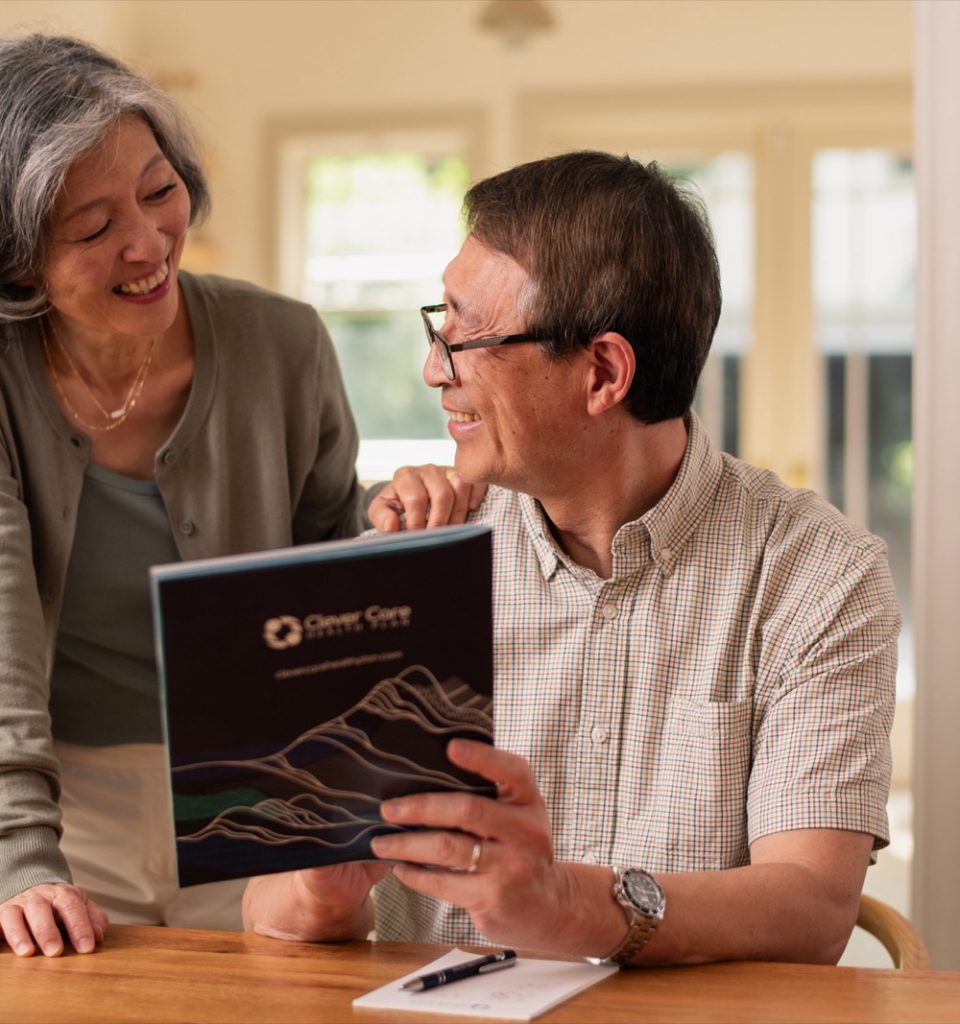 A senior couple reviewing a Clever Care plan booklet at home