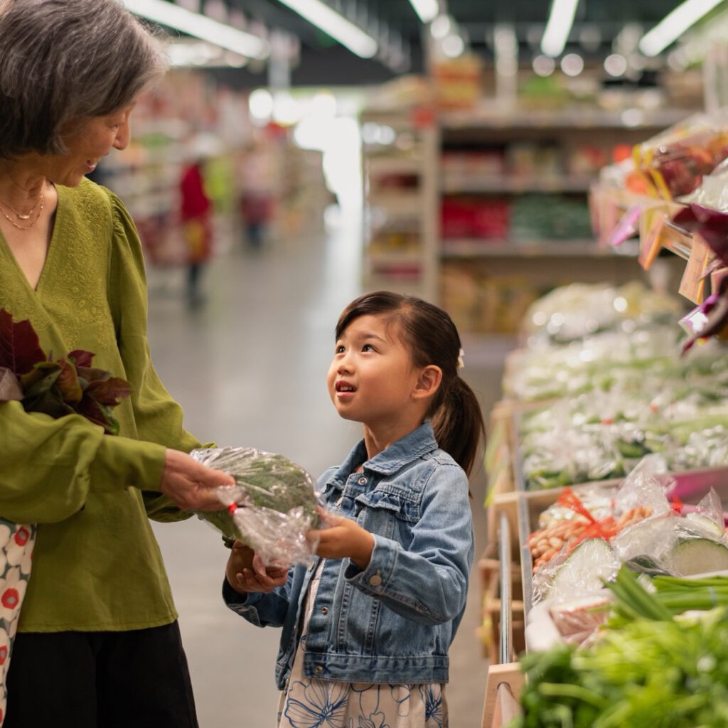 A grandmother and grandchild shopping for fresh produce at a market